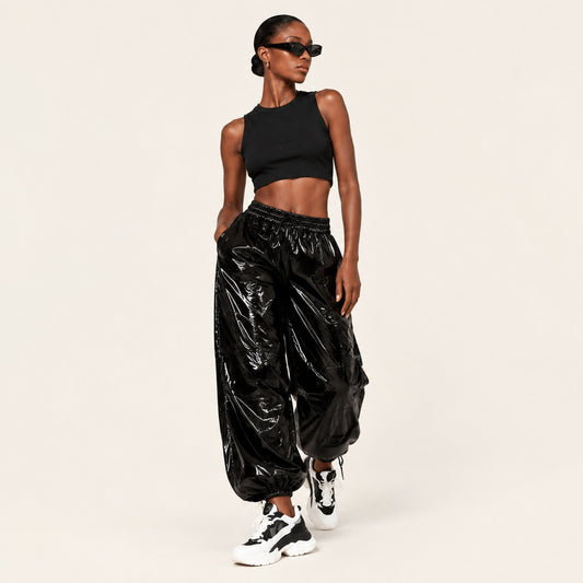 Model wearing black wet-look faux leather high-waisted cargo joggers